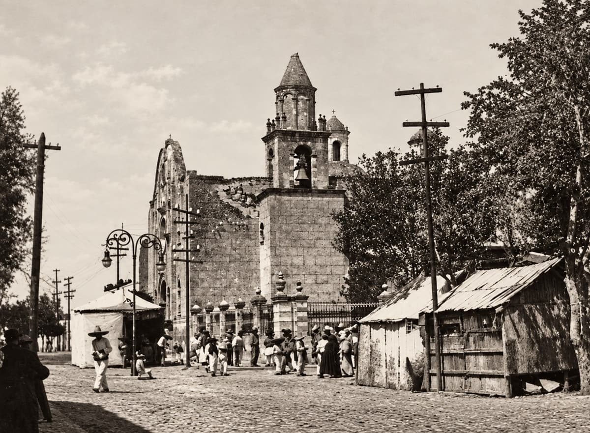 Fotografía antigua del templo del Sagrado Corazón de Jesús, con casetas de madera y gente en la calle empedrada